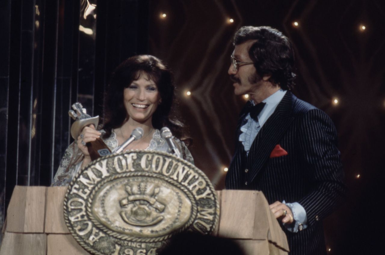 Lynn accepts the award for Entertainer of the Year from Marty Robbins at the 1976 Academy of Country Music Awards.