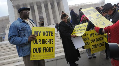 Defensores dos direitos de voto distribuem cartazes fora da Suprema Corte dos EUA em 27 de fevereiro de 2013, enquanto o tribunal se prepara para ouvir Shelby County vs Holder.