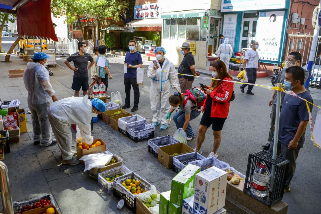 Residents stand behind a cordon line at a fruit stall in the Tianshan district of Urumqi, Xinjiang, China, on September 5.