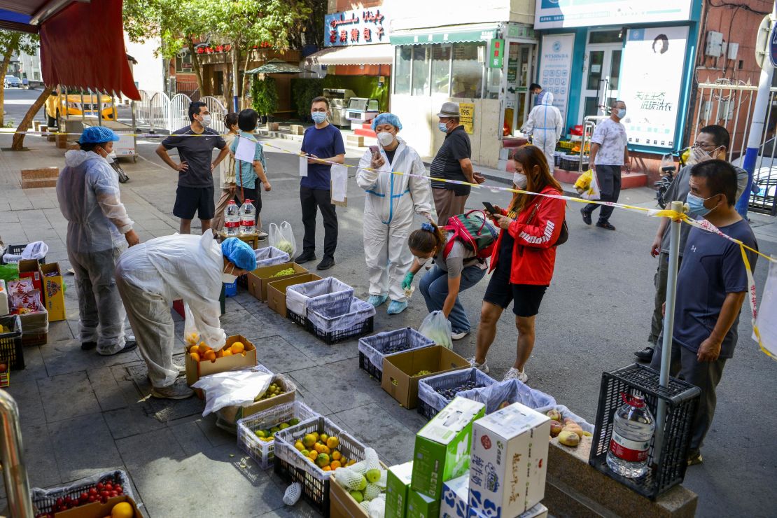 Residents stand behind a cordon line as they shop at a fruit stall in Urumqi, Xinjiang Uyghur Autonomous Region, China, on September 5.