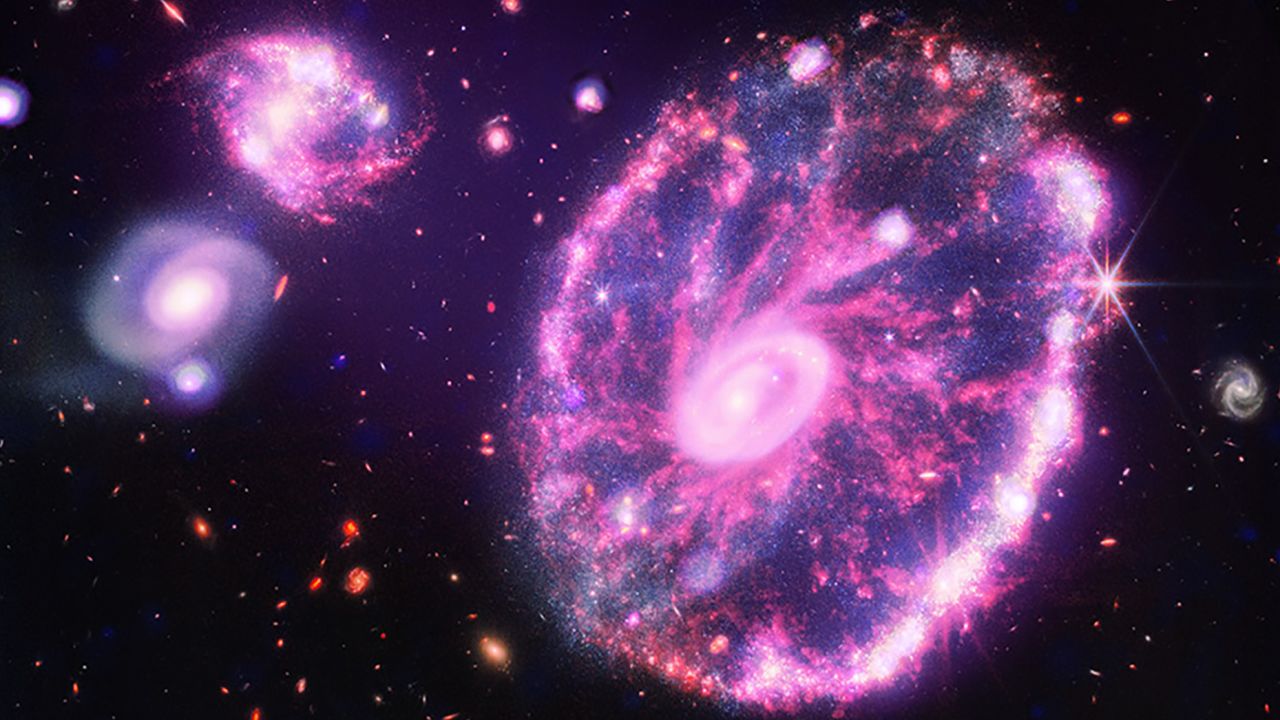 The James Webb Space Telescope's image of the Cartwheel galaxy glows with purple X-ray light captured by the Chandra X-ray Observatory.