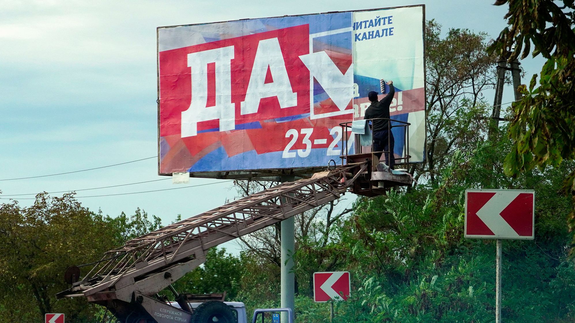 A man glues a <a href="https://edition.cnn.com/2022/09/29/europe/annexation-russia-ukraine-analysis-intl/index.html" target="_blank">referendum</a> poster reading "Yes" in Berdyansk, Ukraine, on September 26. Russia is attempting to annex up to 18% of Ukrainian territory, with President Vladimir Putin expected to host a ceremony in the Kremlin to declare four occupied Ukrainian territories part of Russia.
