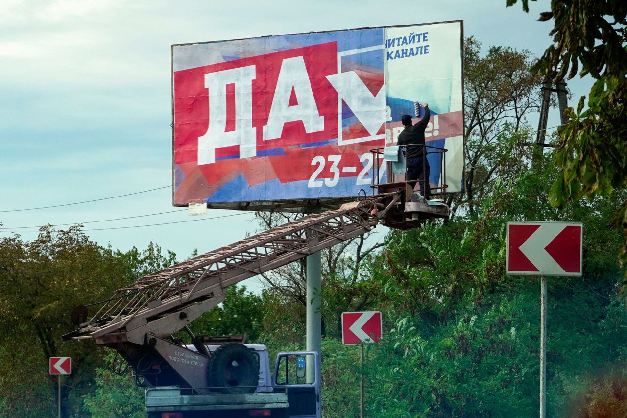 A man glues a <a href="https://edition.cnn.com/2022/09/29/europe/annexation-russia-ukraine-analysis-intl/index.html" target="_blank">referendum</a> poster reading "Yes" in Berdyansk, Ukraine, on September 26. Russia is attempting to annex up to 18% of Ukrainian territory, with President Vladimir Putin expected to host a ceremony in the Kremlin to declare four occupied Ukrainian territories part of Russia.