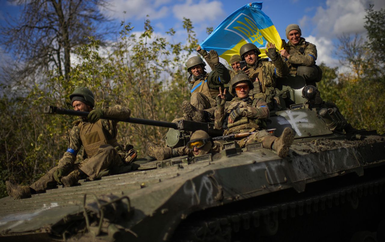 Ukrainian soldiers sit on an armored vehicle as they drive on a road between Izium and Lyman in Ukraine, on October 4, as the <a href=