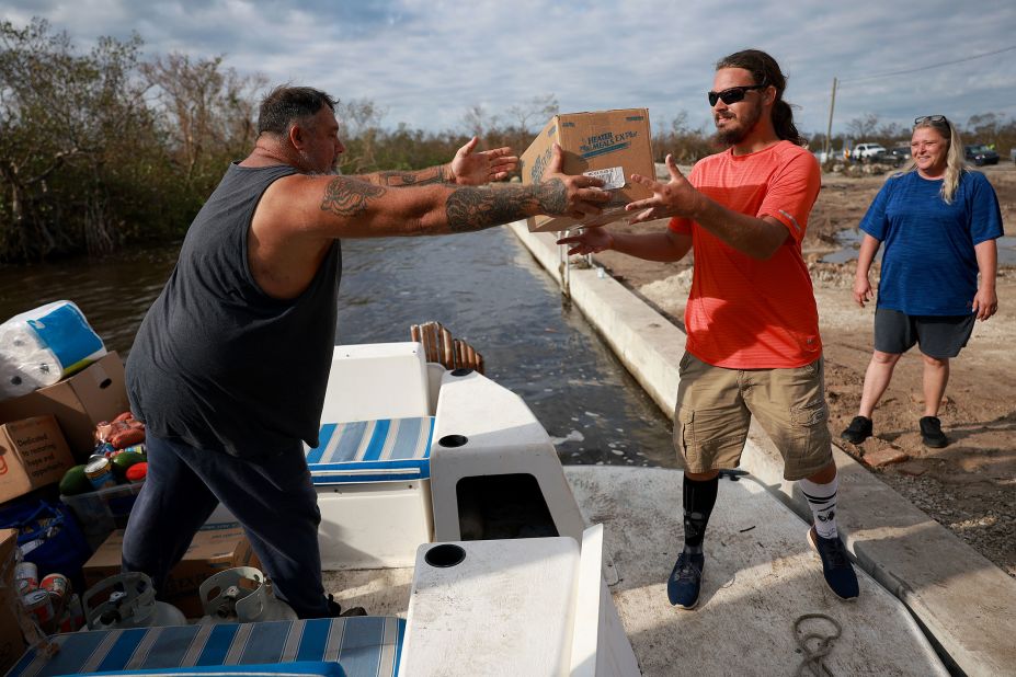 Greg Guidi, left, and Thomas Bostic unload supplies from a boat on Pine Island, Florida, on Tuesday, October 4. With the roads onto the island made impassable, people were getting supplies to the island by boat.