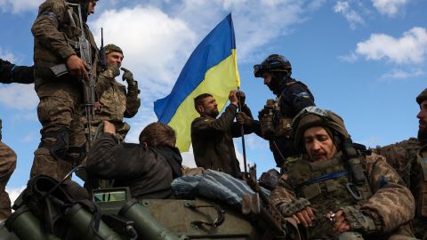 Ukrainian soldiers adjust a national flag on an armored personnel carrier on a road near Lyman, Donetsk region on October 4, 2022.