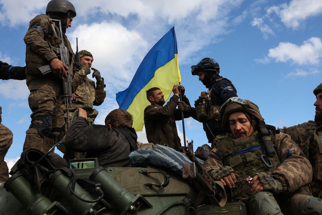 Ukrainian soldiers adjust a national flag on an armored personnel carrier on a road near Lyman, Donetsk region on October 4, 2022.