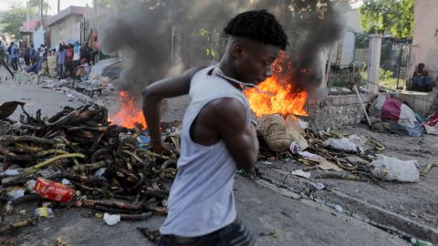 A man walks past a burning street barricade during a protest against the government and rising fuel prices, in Port-au-Prince, Haiti, October 3, 2022.
