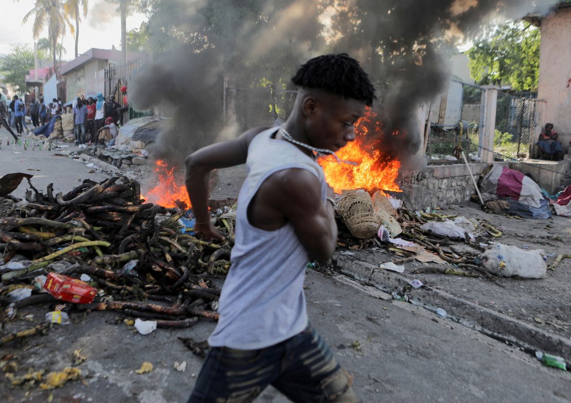 A man runs past a burning street barricade during a protest against the government and rising fuel prices, in Port-au-Prince, Haiti October 3, 2022.