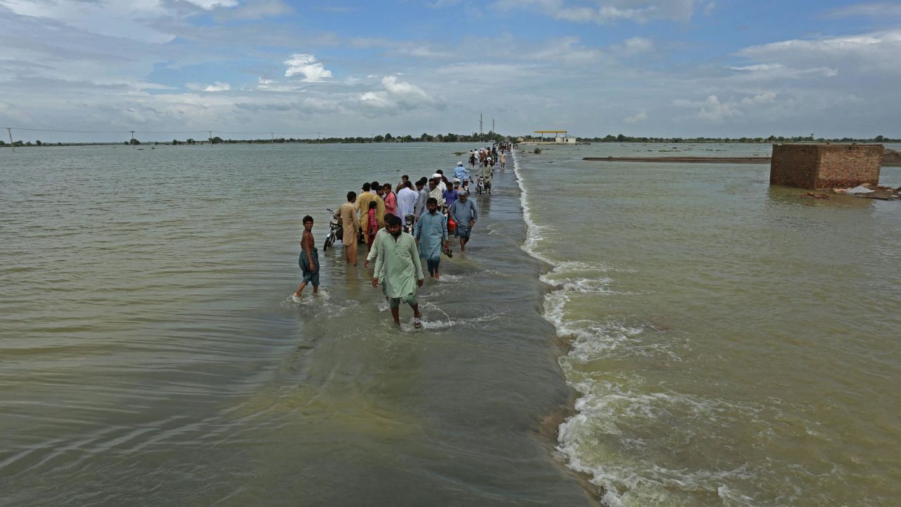 TOPSHOT - Stranded people wade through a flooded area after heavy monsoon rainfall in Rajanpur district of Punjab province on August 25, 2022. - Figures from the national disaster agency showed on August 25 that 903 people had died in the floods since June, and over 180,000 were forced to flee their rural homes. (Photo by Shahid Saeed MIRZA / AFP) (Photo by SHAHID SAEED MIRZA/AFP via Getty Images)