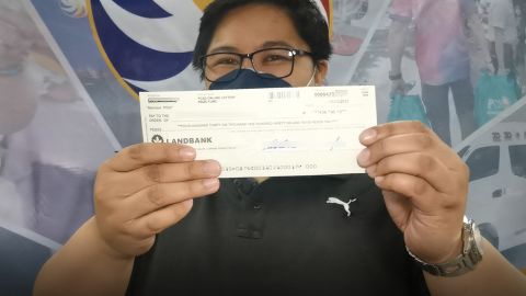 A  lottery winner holds up her check.