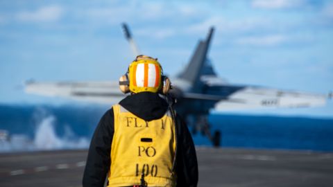 A worker watches the launch of an F/A-18E Super Hornet aboard a US aircraft carrier in the Sea of ​​Japan on October 5.
