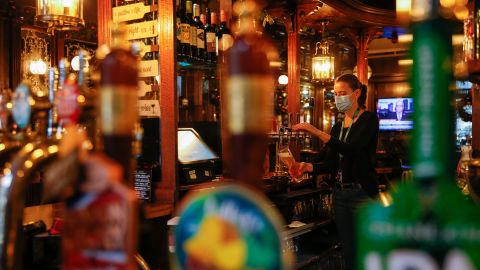 A member of staff pulls a pint at the Paxtons Head pub in London, early December 2020, as English businesses temporarily emerge from lockdown.