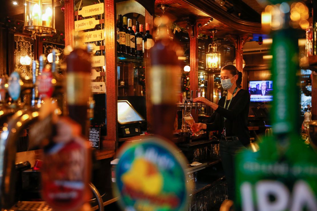 A member of staff pulls a pint at the Paxtons Head pub in London, early December 2020, as England businesses temporarily emerged from lockdown. 