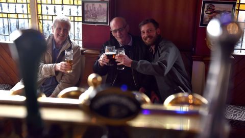 Tres amigos se reúnen en el pub Cornucopia en Southend, Inglaterra, después de que en mayo de 2021 se levantaran las restricciones pandémicas sobre la mezcla de hogares en el interior. 