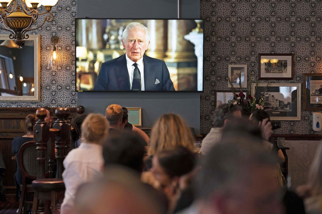 Decades later, a pub in Piccadilly comes to a standstill as patrons watch King Charles III address the nation in his first speech as King of England, in September. 