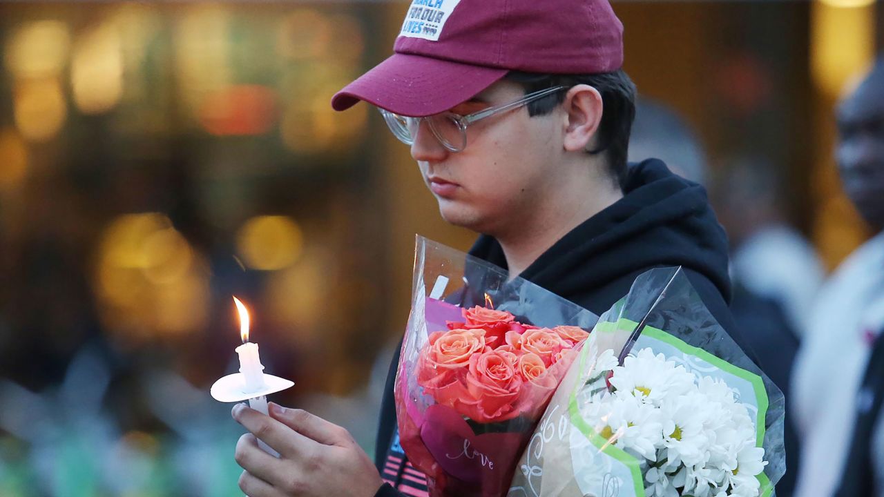 Robert Schentrup holds flowers and a candle during a candlelight vigil at Memory Mall on the University of Central Florida campus in Orlando, Florida, on the one-year anniversary of the mass shooting at Marjory Stoneman Douglas High School, on Thursday, February 14, 2019.
