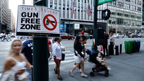 People walk past a "Gun Free Zone" sign posted near Bryant Park at one of the access points to Times Square on September 3, 2022 in New York.