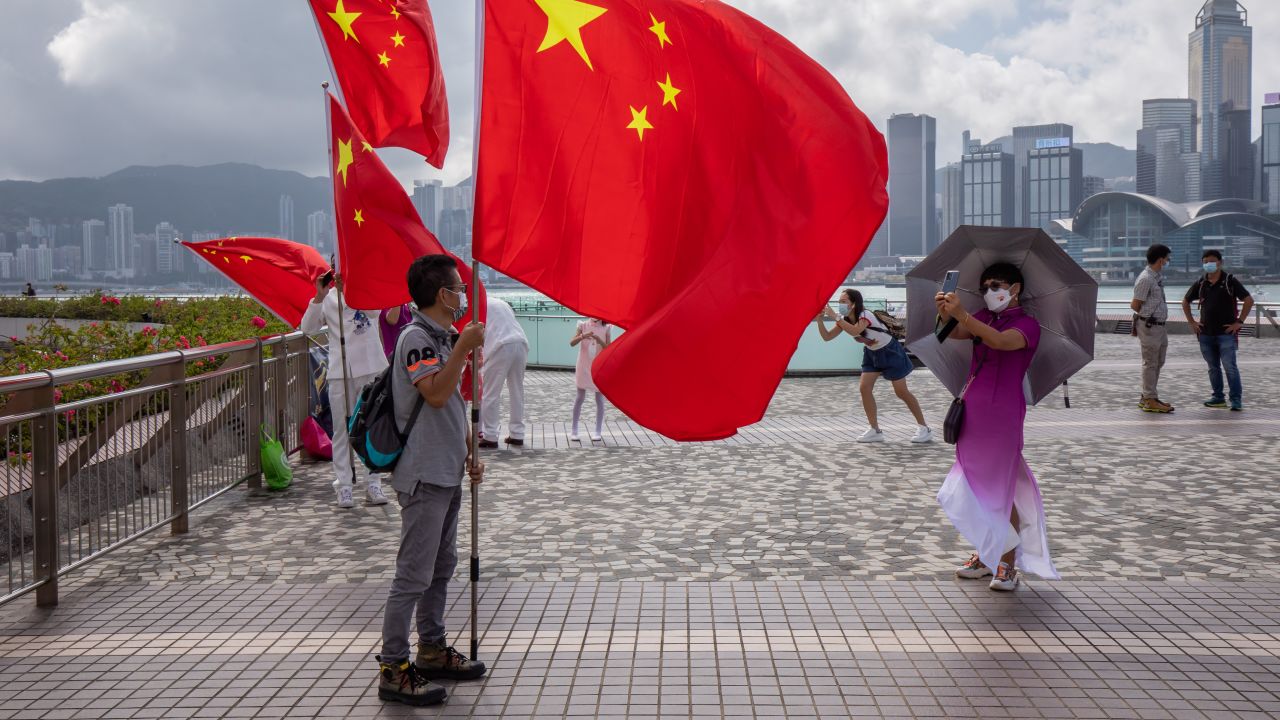 A man poses for a photograph with a flag of China while celebrating Chinese National Day in Hong Kong, on Saturday, October 1, 2022. 