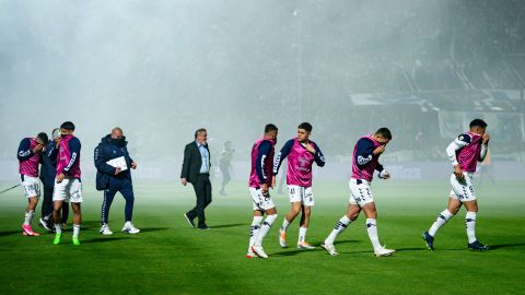 Players react after being affected by tear gas during the match. 