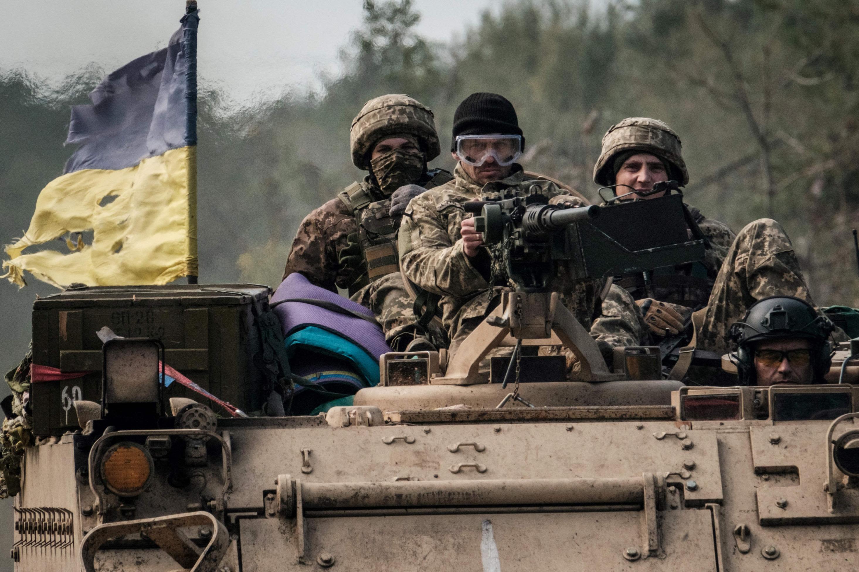 Ukrainian soldiers ride on an armored vehicle near the recently retaken town of Lyman in Donetsk region on October 6.