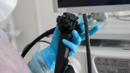 An endoscopist in blue gloves holds an endoscope in his hands. In the frame only the hands with the device are close-up. High quality photo
