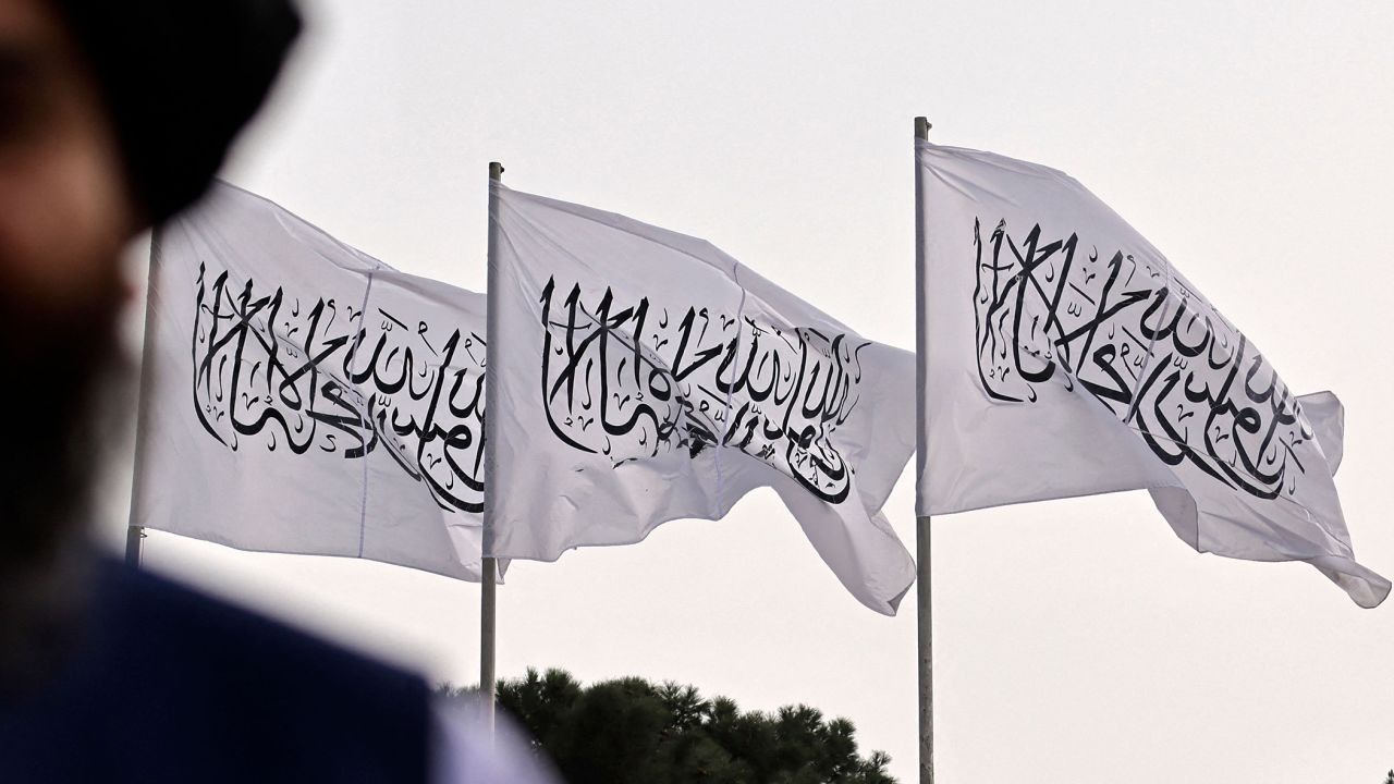 A Taliban fighter is pictured against the backdrop of Taliban flags installed at the Hamid Karzai International Airport in Kabul on September 11, 2021. 