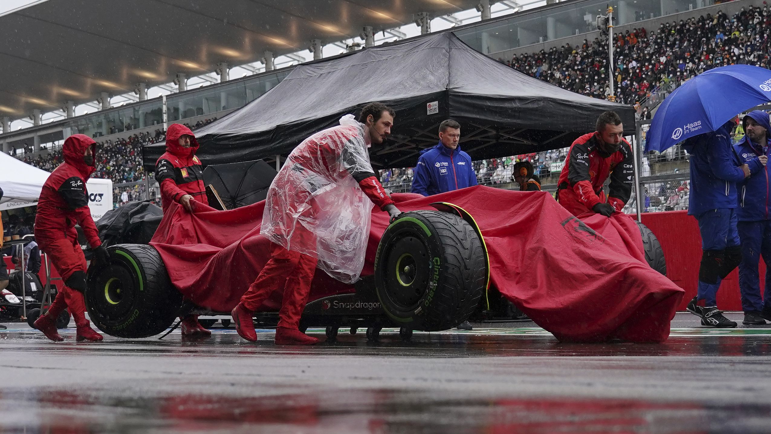 Carlos Sainz's car is carried in the pit lane during the rain delay.