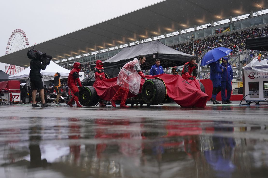 Carlos Sainz's car is carried in the pit lane during the rain delay.