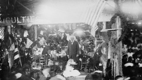 Frederick Douglass delivering a speech in a crowded room in 1892.