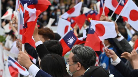 Lawmakers from Taiwan and Japan wave flags at a ceremony to mark the island's National Day in front of the Presidential Office in Taipei on October 10, 2022. 