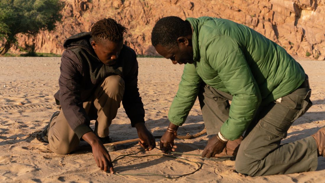Pictured, Kasaona teaching Taiwin Garoeb how to track elephants.