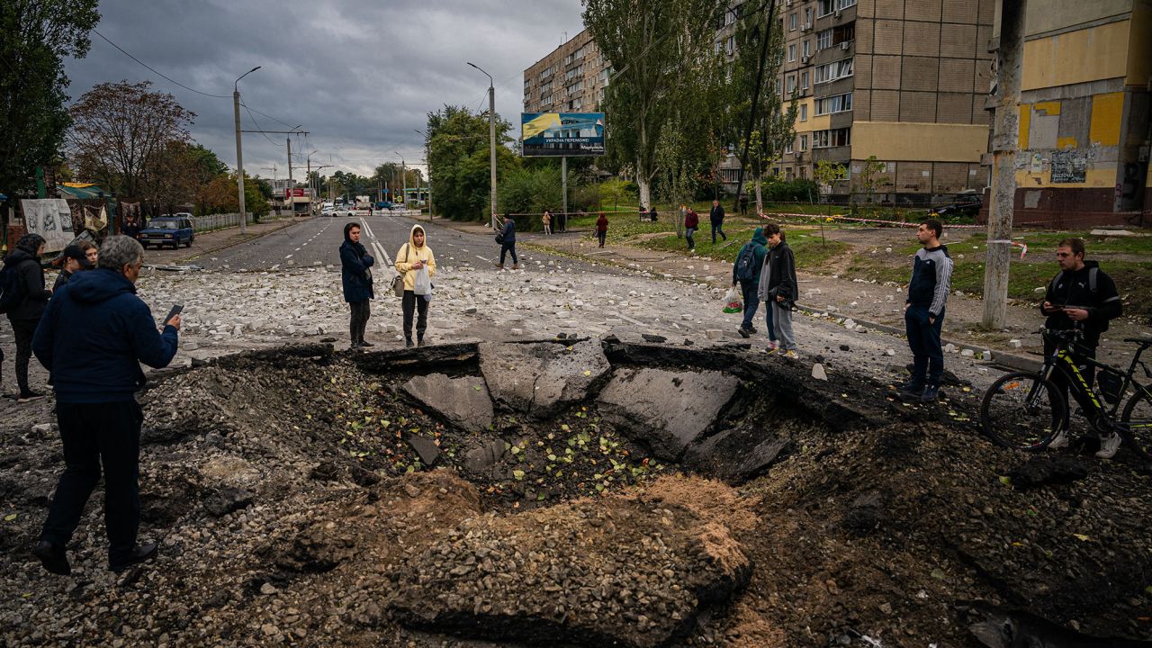 Local residents examine a crater following a missile strike in Dnipro on Monday.