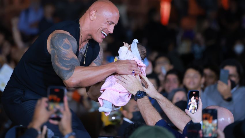 MEXICO CITY, MEXICO - OCTOBER 03: Dwayne Johnson holds a fan's baby during the black carpet for the 'Black Adam Fan Event' at Museo Anahuacalli on October 03, 2022 in Mexico City, Mexico. (Photo by Hector Vivas/Getty Images)