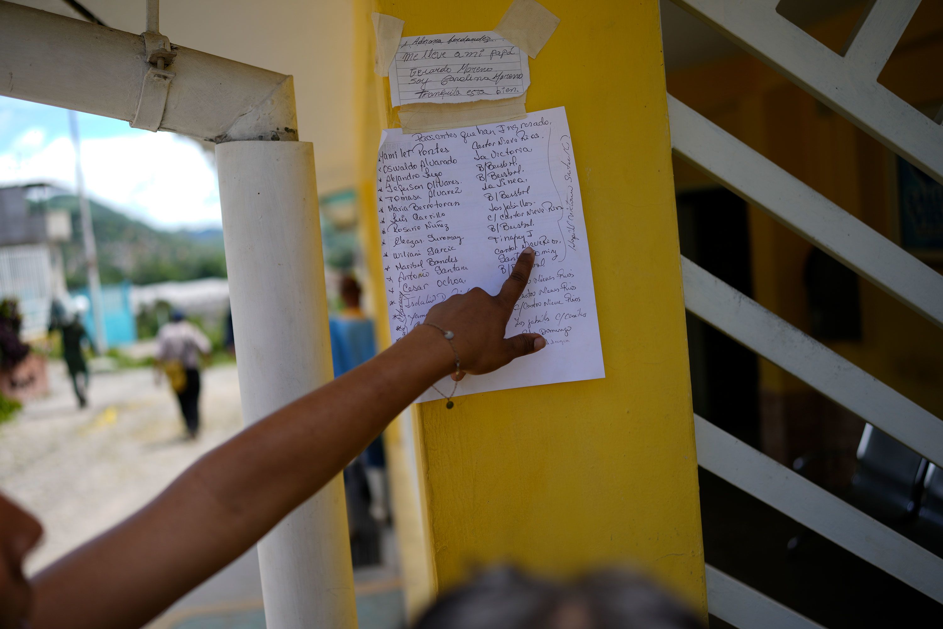 A person points to a list of names of people affected by flooding who were checked into a community center in Las Tejerias on Monday. The bodies of victims are also brought here.