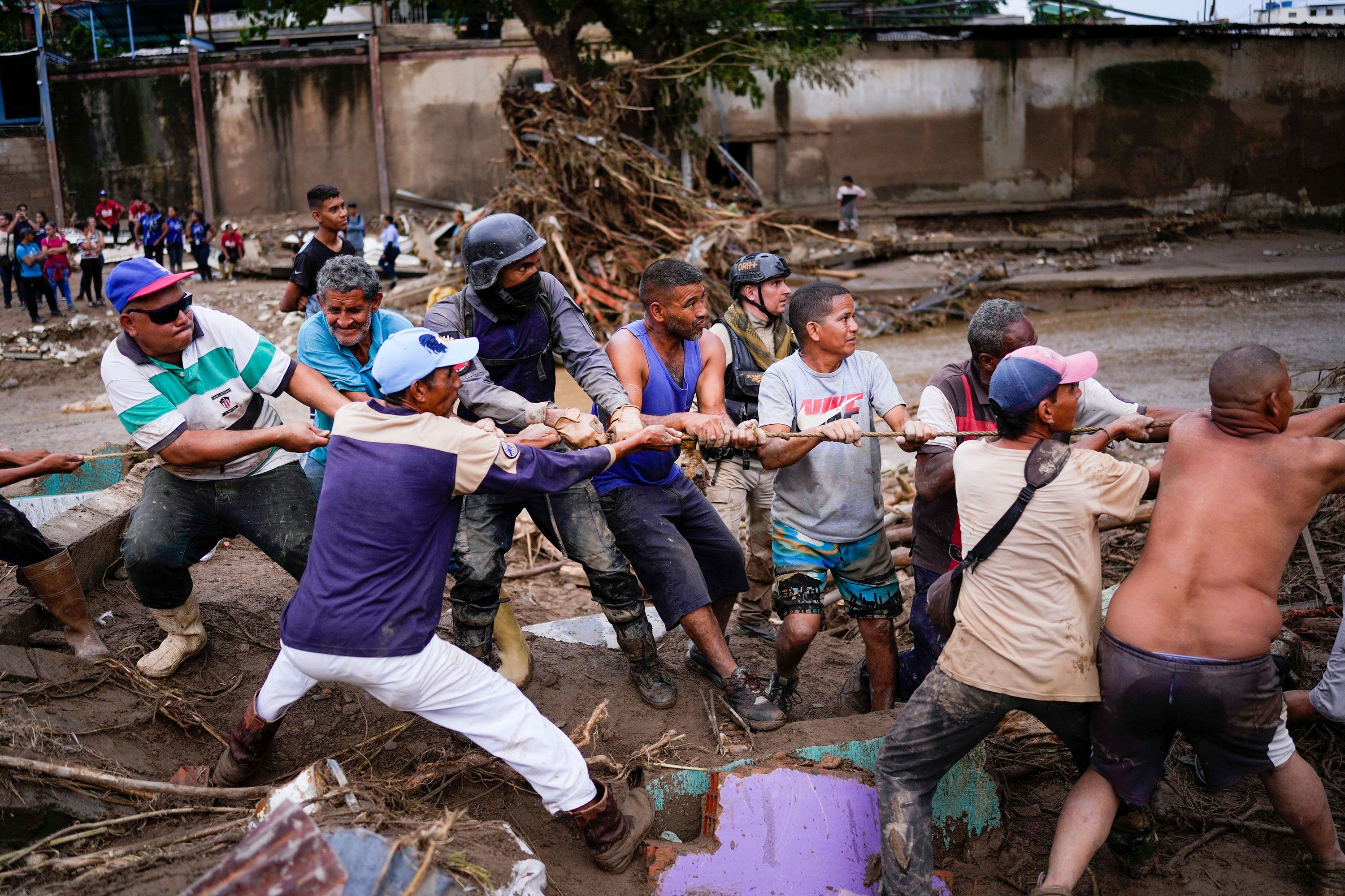 Local residents and relief workers pull a rope to remove wreckage in search of survivors on Sunday.