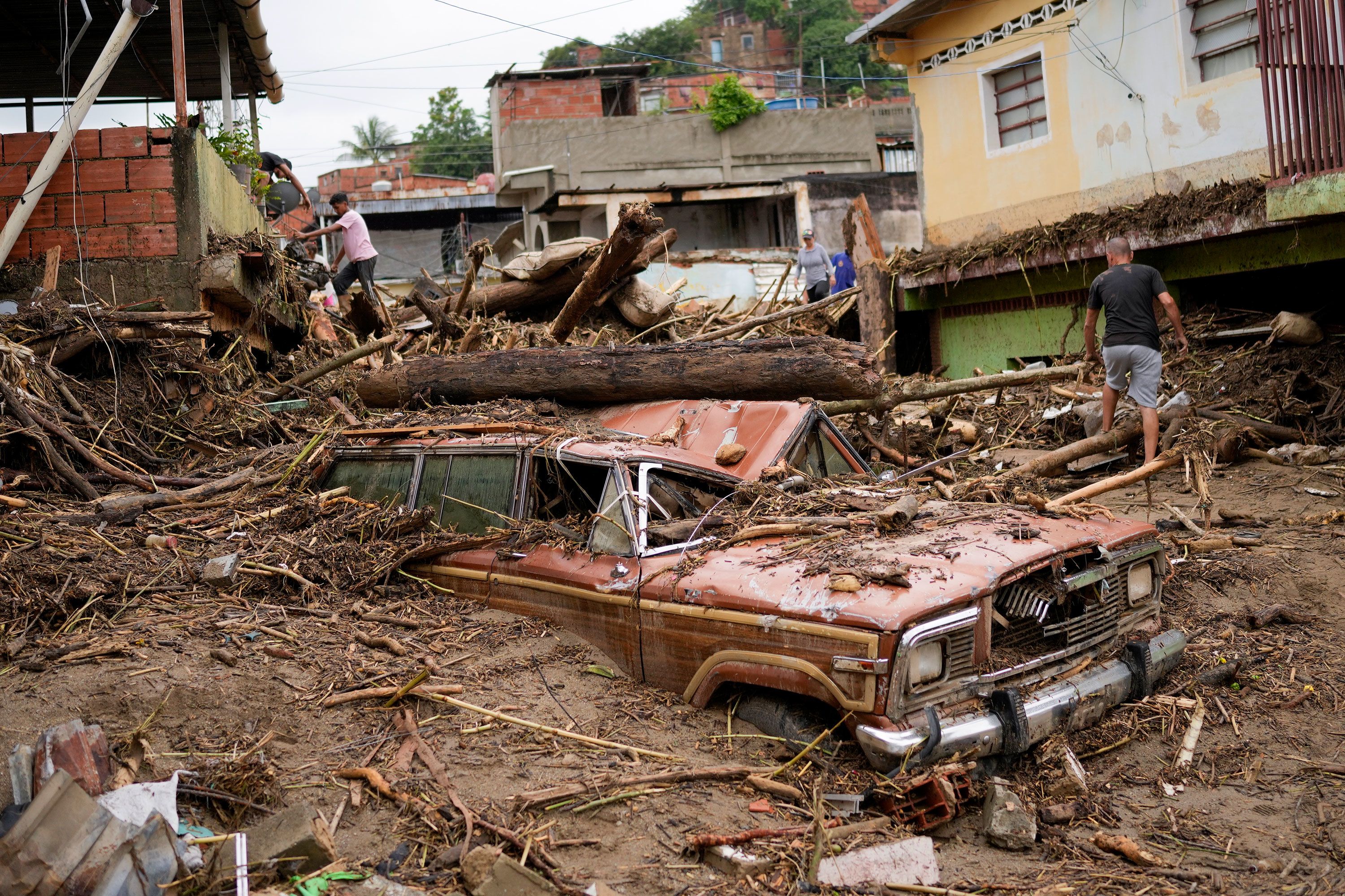 Residents walk through the debris left by the landslide on Sunday.