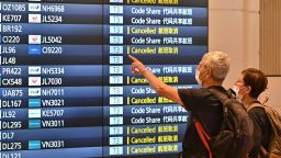 Travellers look at an arrivals board after arriving at the international terminal of Tokyo's Haneda Airport on October 11, 2022, as Japan reopened to foreign travellers after two-and-a-half years of Covid restrictions. (Photo by Richard A. Brooks / AFP) (Photo by RICHARD A. BROOKS/AFP via Getty Images)
