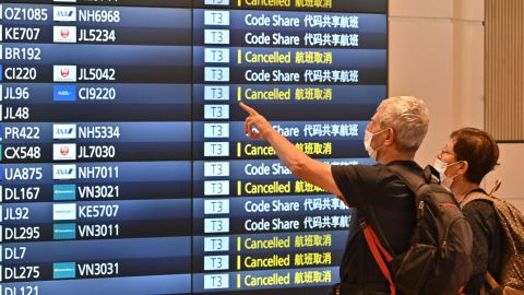 Travellers look at an arrivals board after arriving at the international terminal of Tokyo's Haneda Airport on October 11, 2022.