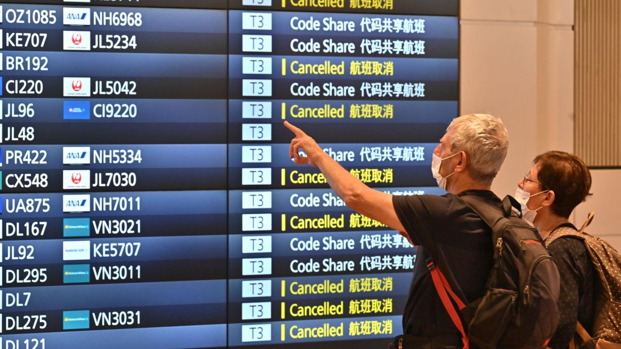 Travellers look at an arrivals board after arriving at the international terminal of Tokyo's Haneda Airport on October 11, 2022.