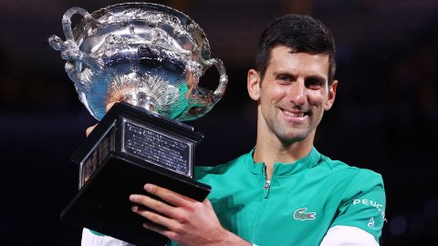 Djokovic memegang Piala Tantangan Norman Brookes saat dia merayakan kemenangan di Australia Terbuka 2021.