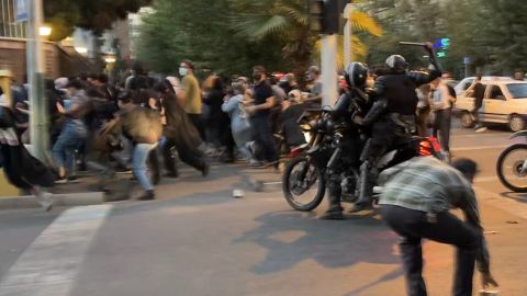 An Iranian police officer on a motocycle raises a baton to disperse protesters last month.