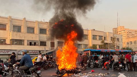 People gather next to a burning motorcycle in Tehran amid the protests on October 8.