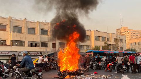 A picture obtained by AFP outside Iran, shows people gathering next to a burning motorcycle in the capital Tehran on October 8, 2022.