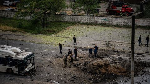 Investigators are examining a crater next to a damaged bus following a missile attack in Dnipro on Monday.