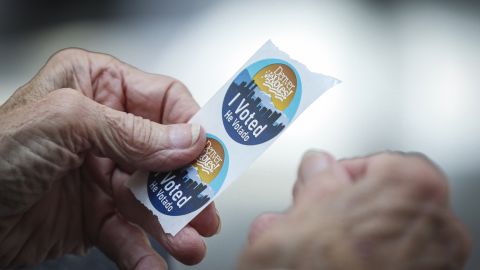 An election judge tears off a couple of "I Voted" stickers to hand to a voter as people cast their ballots in the State Primaries on June 28, 2022 at the Wellington E. Webb Municipal Office Building in Denver, Colorado. 