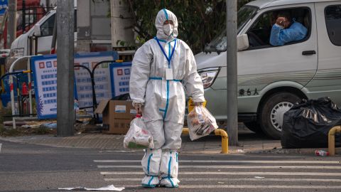 Un trabajador con equipo de protección cruza una carretera cerca de un área cerrada debido a la COVID-19 en Beijing, China, el 12 de octubre de 2022.