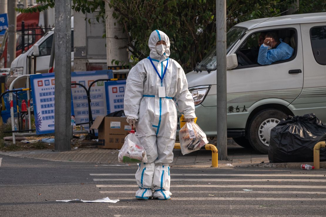 A worker wearing protective gear crosses the road near an area placed under lockdown due to Covid-19 in Beijing, China on October 12, 2022.