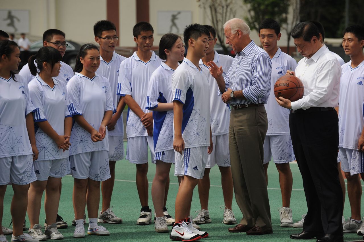 Xi signs a basketball as US Vice President Joe Biden talks with a student at a high school outside Chengdu, China, in 2011.