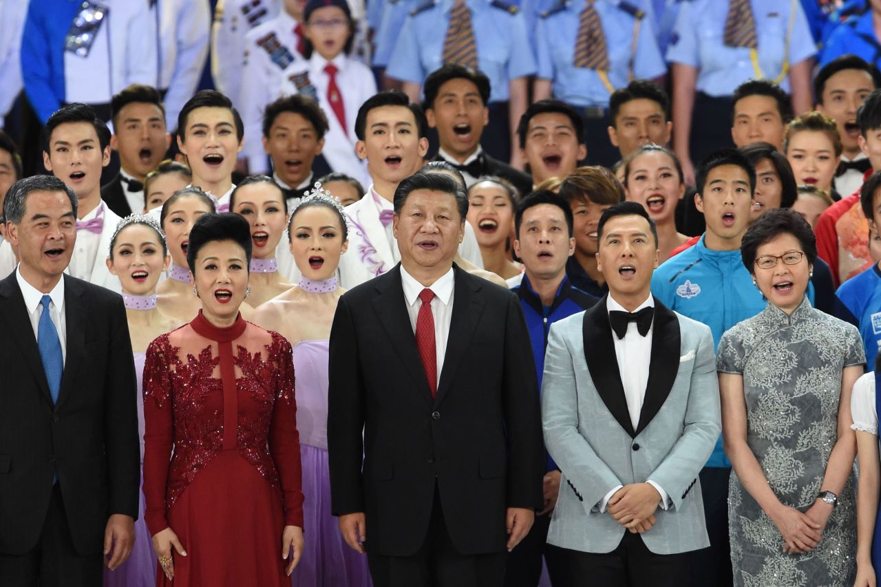 Xi joins Hong Kong's outgoing chief executive Leung Chun-ying, seen at left, and incoming replacement Carrie Lam, right, in singing the song "My Country" at the end of a variety show in Hong Kong in June 2017. Standing next to Xi are performers Lisa Wang and Donnie Yen.